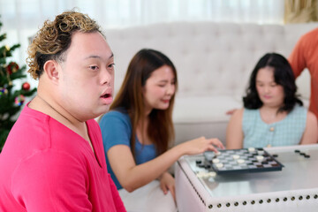 A man with down syndrome, gathering of people playing board games at home