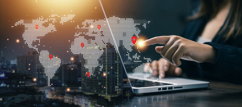 Businesswoman pointing at digital world map with location markers, representing global business network, international trade, logistics, and worldwide communication technology.