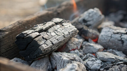 Closeup of charcoal embers glowing in a barbecue grill with a blurred background