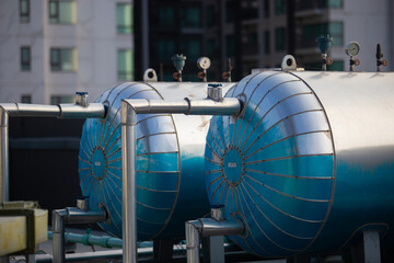 Close-up of industrial pressure tanks and piping system on a building rooftop, representing HVAC...