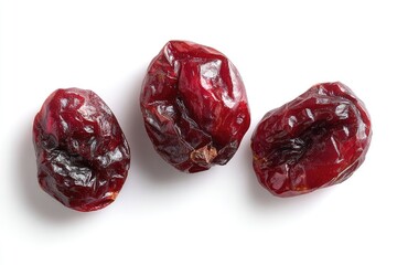 Three dried cranberries, top view,  on white background.  Dark red, wrinkled surfaces, slightly uneven shapes