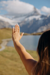 Young woman holding out her hand with an engagement ring against a mountain landscape background