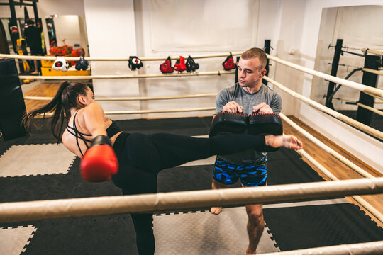 Training session at a martial arts gym featuring a kick and pad work between a coach and a student
