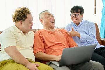 An elderly man is talking with a man with Down syndrome while holding a laptop