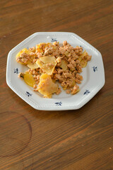 Moussaka, a dish of potatoes and minced meat in a white plate on the table