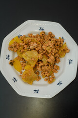 Moussaka, a dish of potatoes and minced meat in a white plate on the table