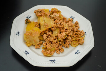 Moussaka, a dish of potatoes and minced meat in a white plate on the table