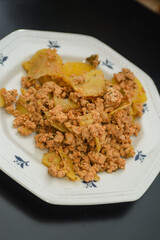 Moussaka, a dish of potatoes and minced meat in a white plate on the table