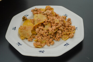 Moussaka, a dish of potatoes and minced meat in a white plate on the table