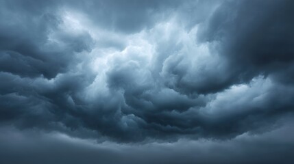 Obraz premium Dramatic Dark Storm Clouds Forming Over a Landscape with Varying Shades of Gray and Blue, Creating an Intense and Foreboding Atmosphere