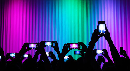 Crowd filming concert with smartphones in front of rainbow stage. An exciting spectacle of audience participation. Live entertainment, shared experiences, public event.