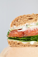 Sandwich with salmon and lettuce leaves on grey background. Close up.