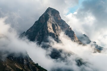 Dramatic Mountain Peak Emerging From Clouds with Warm Light and Textured Rock Face in Harsh Sunlight