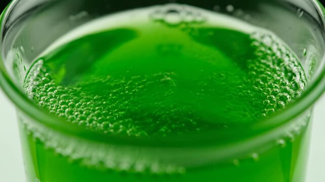 Extreme close-up of a bubbling green potion with effervescent reactions in a glass beaker science, innovation, glass beaker