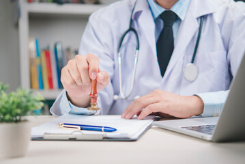 Doctor white coat with stethoscope stamping medical document for approval. Concept  health certificate, insurance claim, diagnosis validation, and healthcare paperwork in  hospital or clinic office.
