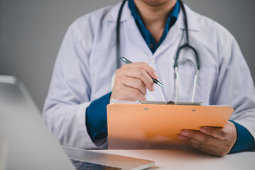 Healthcare and medicine concept. Physician writing on medical chart for patient examination results. Doctor documenting information for insurance claim, diagnosis, or treatment protocol in a clinic.