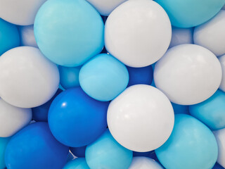Background of balloons of various sizes in shades of dark blue, light blue, and white. Close-up of balloon backdrop arranged tightly in dark blue, light blue, and white for decoration.