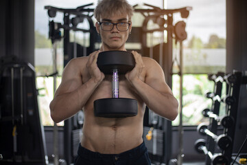 Athletic shirtless handsome young man, muscular young men are exercising with weights in a gym.

