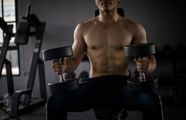 Athletic shirtless handsome young man, muscular young men are exercising with weights in a gym.
