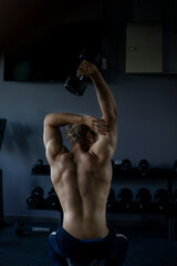 Athletic shirtless handsome young man, muscular young men are exercising with weights in a gym.
