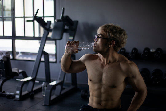Athletic shirtless handsome young man, muscular young men are exercising with weights in a gym.
