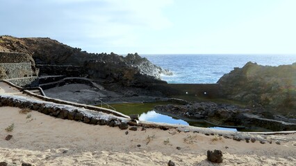 Rocky Lanzarote coastline with volcanic rock, natural tidal pools, sandy coves and carved...