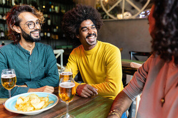 Three diverse male friends enjoying happy hour at brewery bar after work. Friendship concept