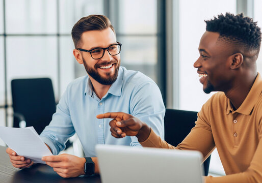 Shared Moment: Capturing a lighthearted moment, two individuals collaborate on a project at an office. Showcasing the power of teamwork, creative ideas and solutions come to life through discussions.
