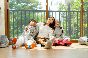 Asian mother, boy and girl as family sit on the floor in front of glass door and look up with happiness after relax of practice in their house.
