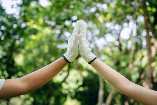 Volunteers environmentalists celebrate successful teamwork high five collaboration in green outdoor park supporting nature community work - Powered by Adobe