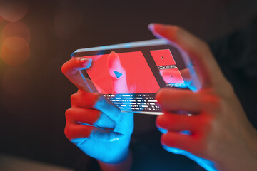 Close-up of hands using a futuristic transparent smartphone to watch online videos, representing next-generation mobile technology, innovation, digital entertainment, and immersive media.