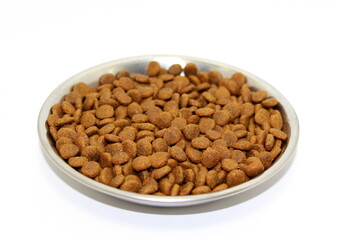 Dry balanced food for cats or dogs in a metal bowl on a white background.