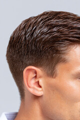 Obraz premium Confident man close up with masculine fade haircut and shiny brown hair. This professional hairstyle shows excellent grooming and clean, modern look for any male model