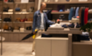 Fototapeta premium man browsing expensive fashion accessories inside blurred, upscale boutique interior, symbolizing consumerism, wealth, and sophisticated retail therapy