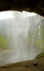 view from behind the water wall of a large waterfall