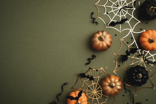 Halloween party background from orange and black pumpkins, bats, spiderweb on dark green table top view. Happy halloween holiday greeting card, flat lay.