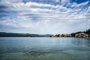 A village on the shore of a sea lagoon under spectacular clouds in the blue sky
