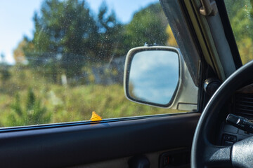 A dry birch leaf on a car window on a rainy autumn day. A trip into nature in an off-road vehicle.