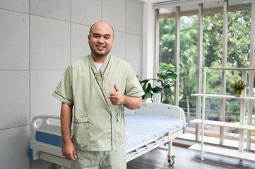 Confident patient stands beside hospital bed, posing in various poses, smiling warmly in gown, showing strength and positivity during recovery in bright and peaceful ward.