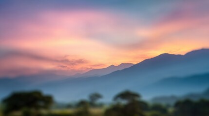 Fototapeta premium A stunning sunset casts soft pink and orange hues over misty mountains. The landscape is serene with silhouettes of trees adding to the peaceful ambiance.