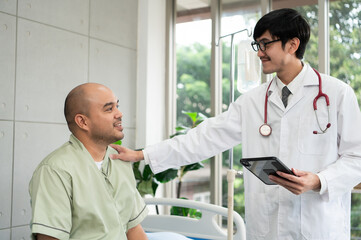 The doctor talks and encourages the patient about treatment options using a digital tablet, promoting clear communication and trust in a bright and supportive hospital environment.