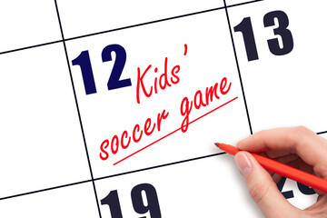 12 th day of the month. Hand writing Kids' soccer game reminder and drawing a line on calendar. Concept of sport and fitness activity. Planning and scheduling