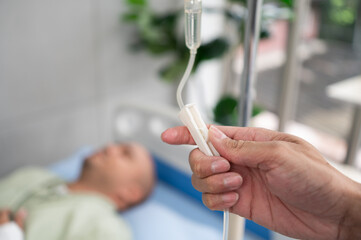 The doctor is adjusting the IV fluid flow for a patient lying on the hospital bed.