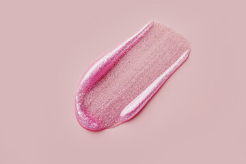 Glittery pink lip gloss smear on soft pink background