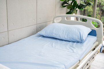 A hospital bed with blue sheets in a fresh and peaceful hospital room.
