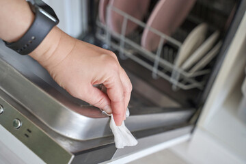 Female hand cleaning dishwasher with wipe in kitchen interior hygiene chores household cleaning...
