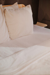 A neatly made bed with crisp white sheets and fluffy pillows in a softly lit room. The warm tones create a relaxing atmosphere.