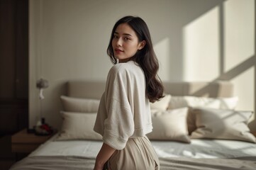 Woman turning back in bedroom with soft light and neutral tones  