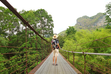 Traveler on the Suspension Bridge with Mt. Thepphitak, a Heart Shaped Mountain stunning View,  Located near the Entrance of Ratchaprapha Dam (Chiao Lan Dam), Surat Thani, Thailand