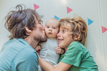 Father, son, and newborn baby lying on the floor in a cozy nursery, celebrating the arrival of their newest family member. Parenthood, bonding, and family love concept